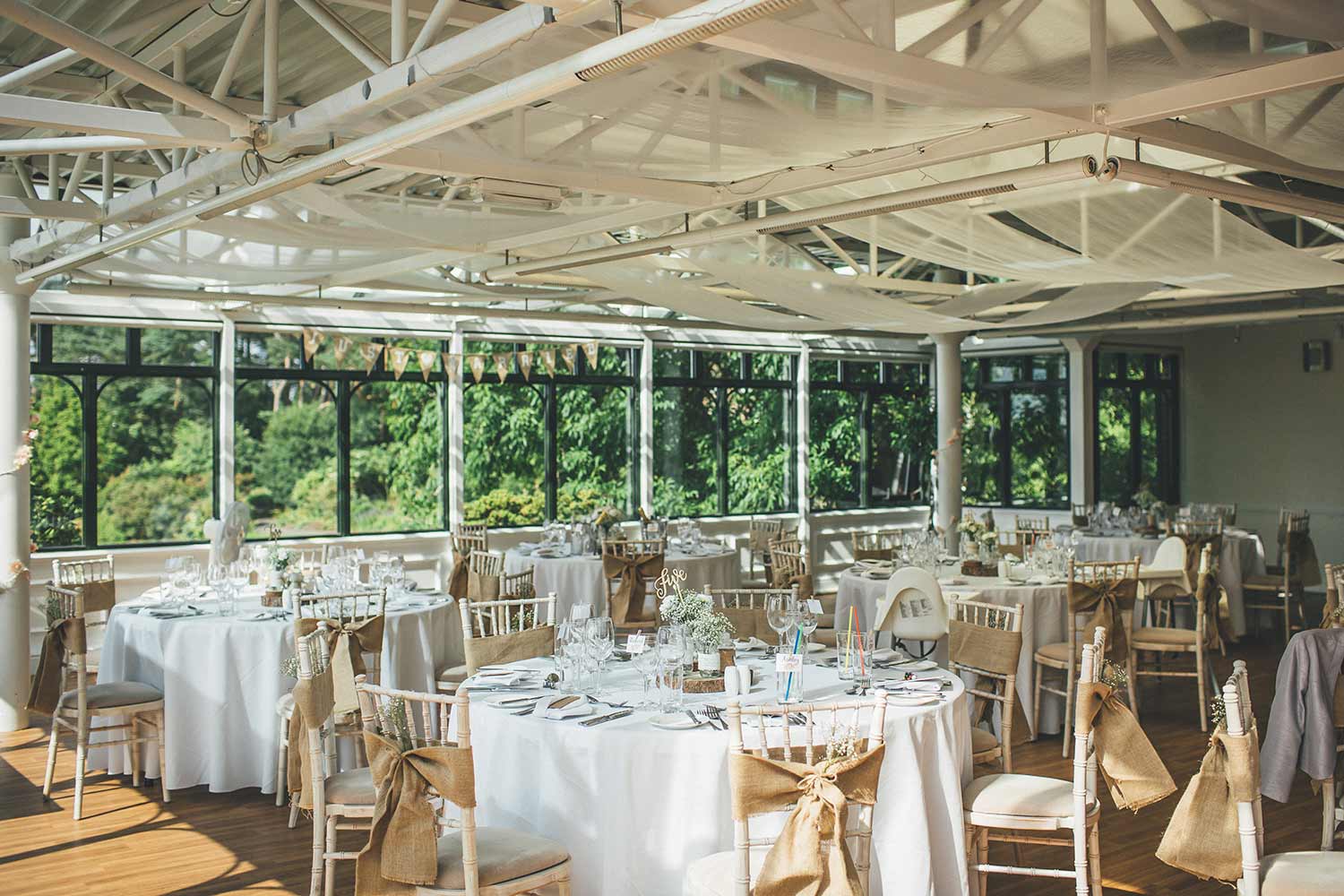 Tables set in the Hulme Conservatory in readiness for a wedding reception.