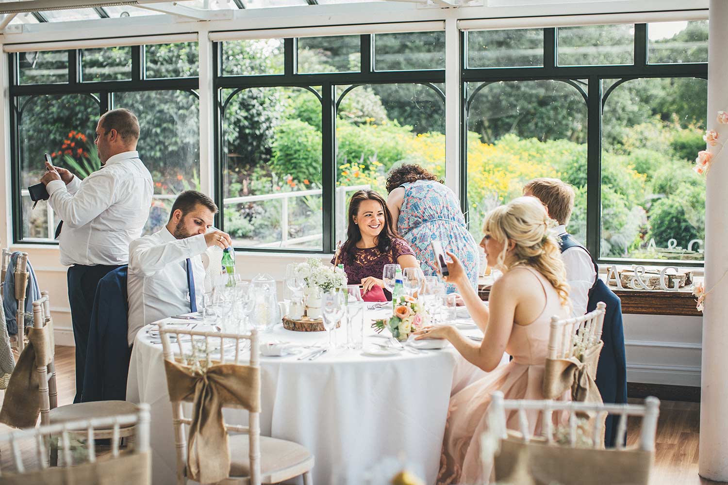 Guests sit round a table during a wedding reception in the Hulme Conservatory.