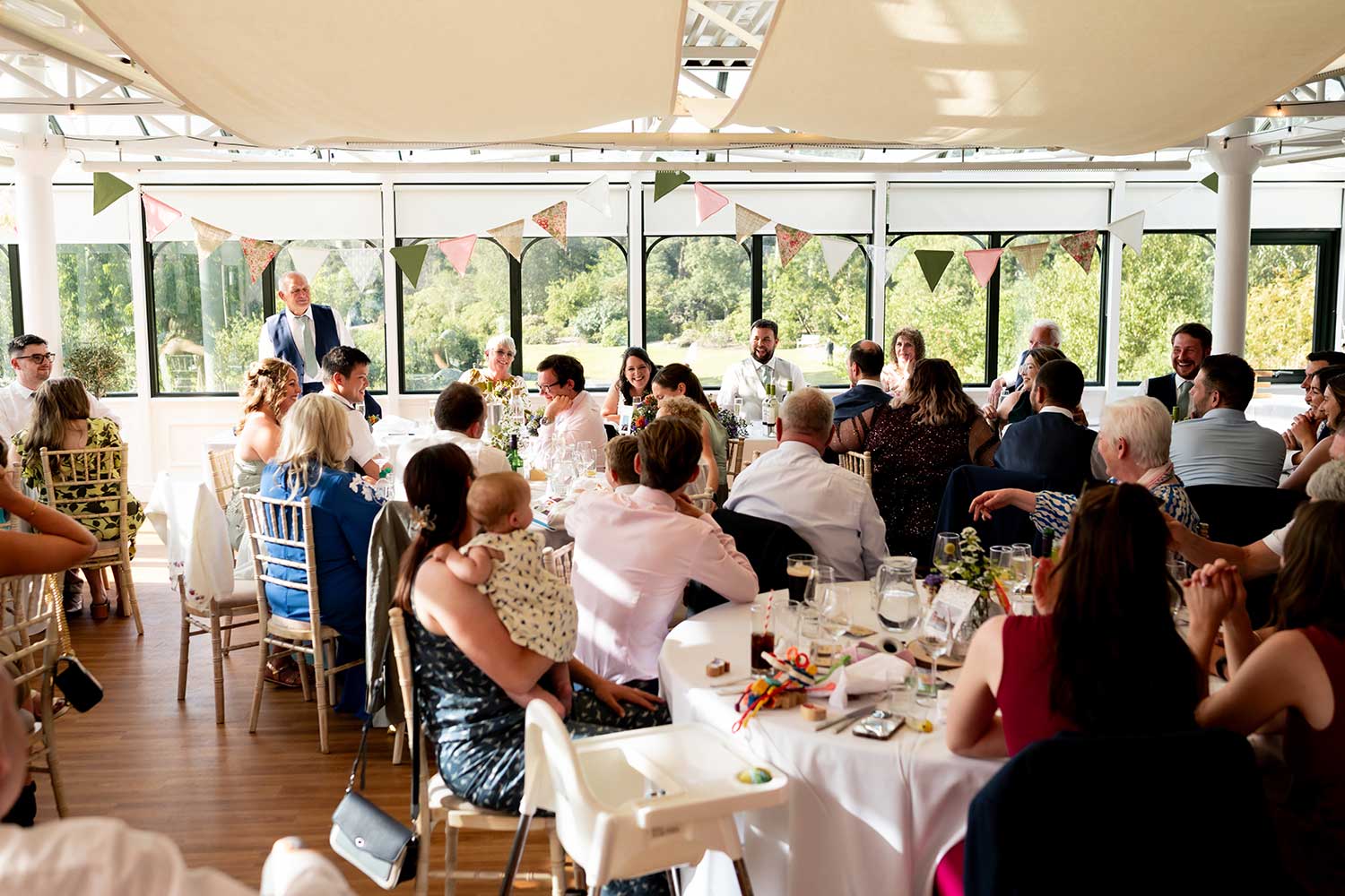 Guests listen to a speech during a wedding reception in the Hulme Conservatory.