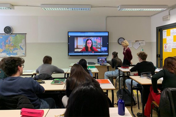A person addressing students via video link.