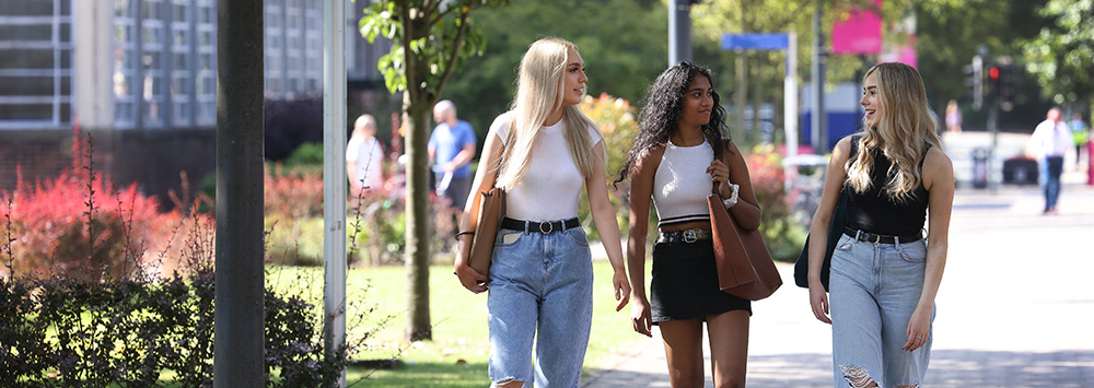 Three female students walking across campus