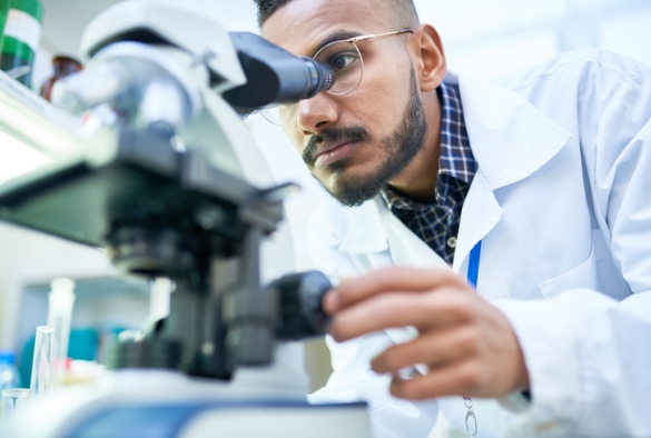 A scene of a man looking into a microscope to analyse a sample