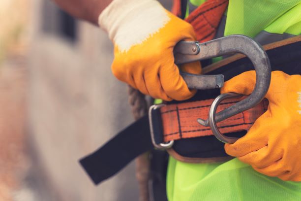 Gloved hand gripping a quick release safety latch on a climbing belt