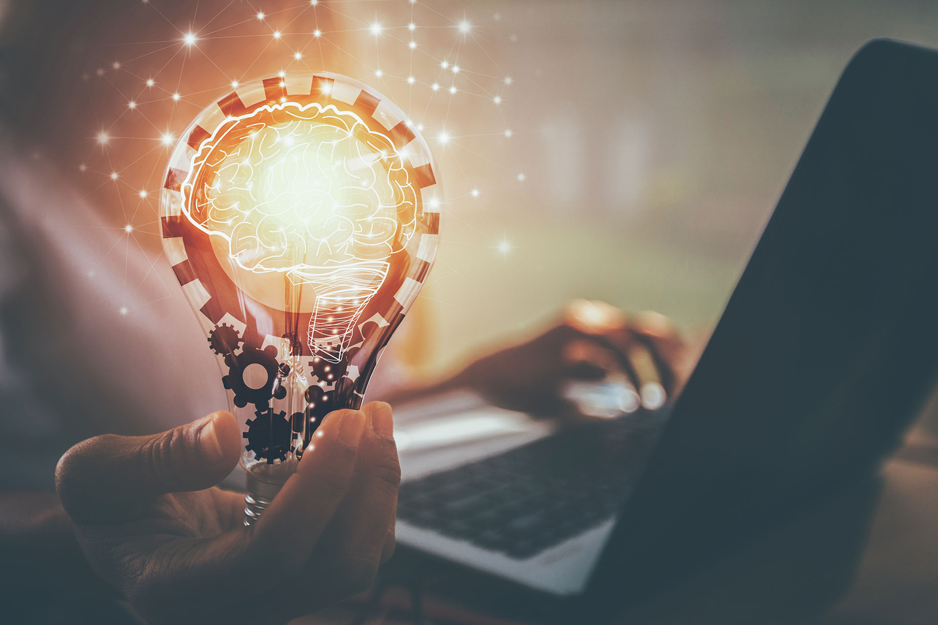 Woman holding abstract lightbulb while working on laptop