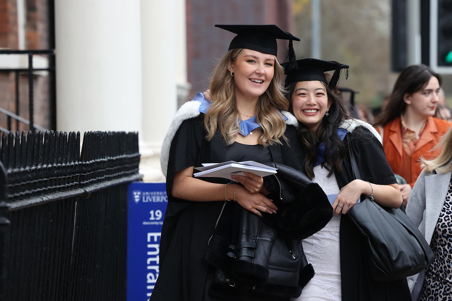 Two students wearing caps and gown celebrate graduation