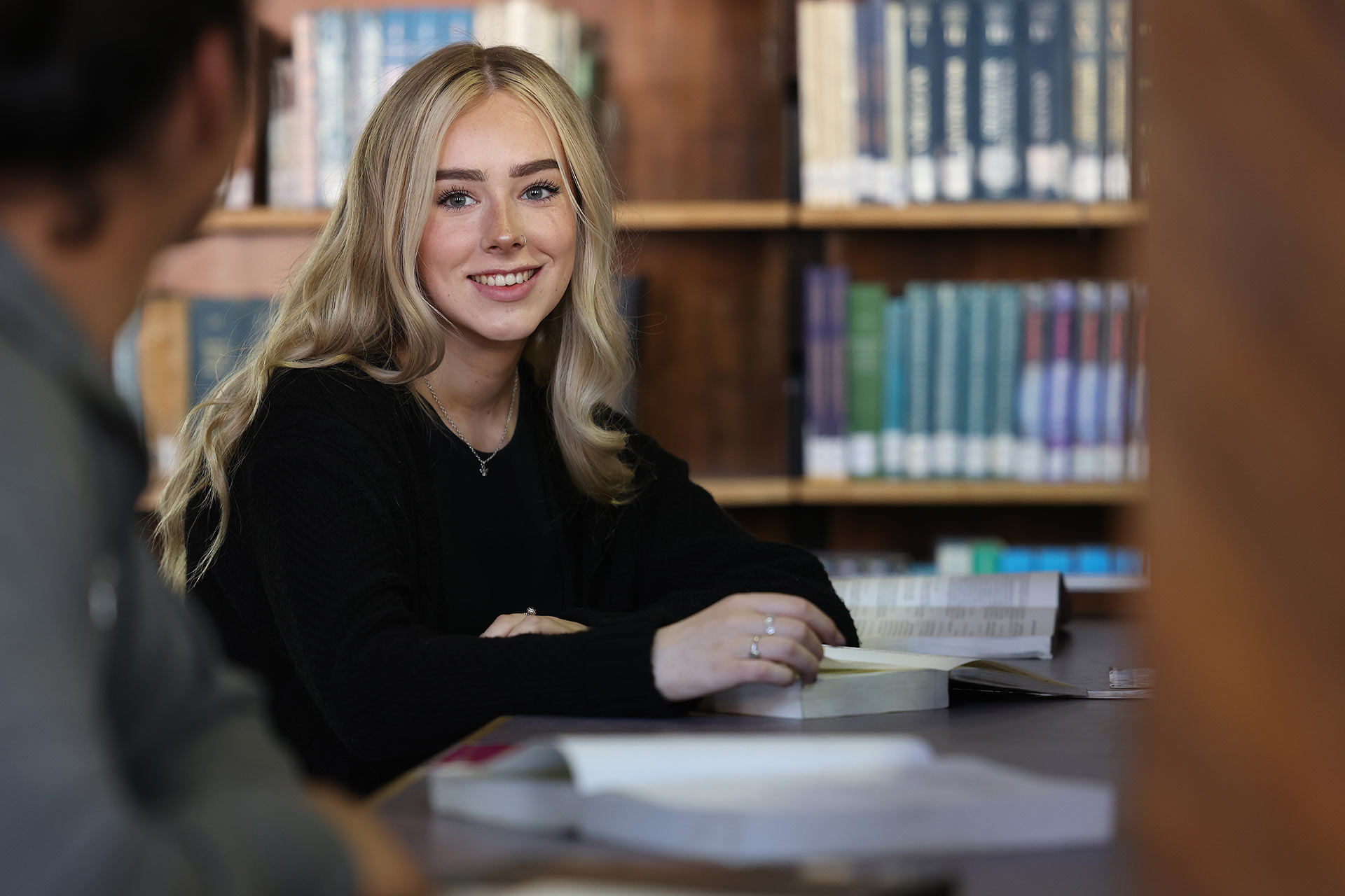 Student sitting at a study desk surrounded by books