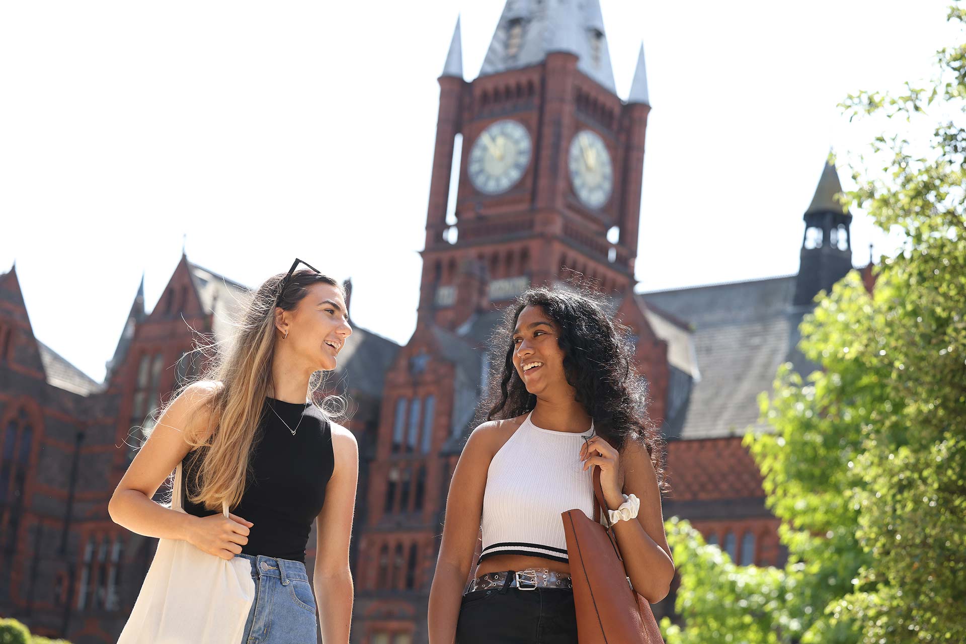 Two smiling students walking together in front of the Victoria Galley and Museum on the University of Liverpool campus