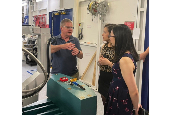 chris lucas and 2 women standing around a machine in a factory, discussing its operation and maintenance.