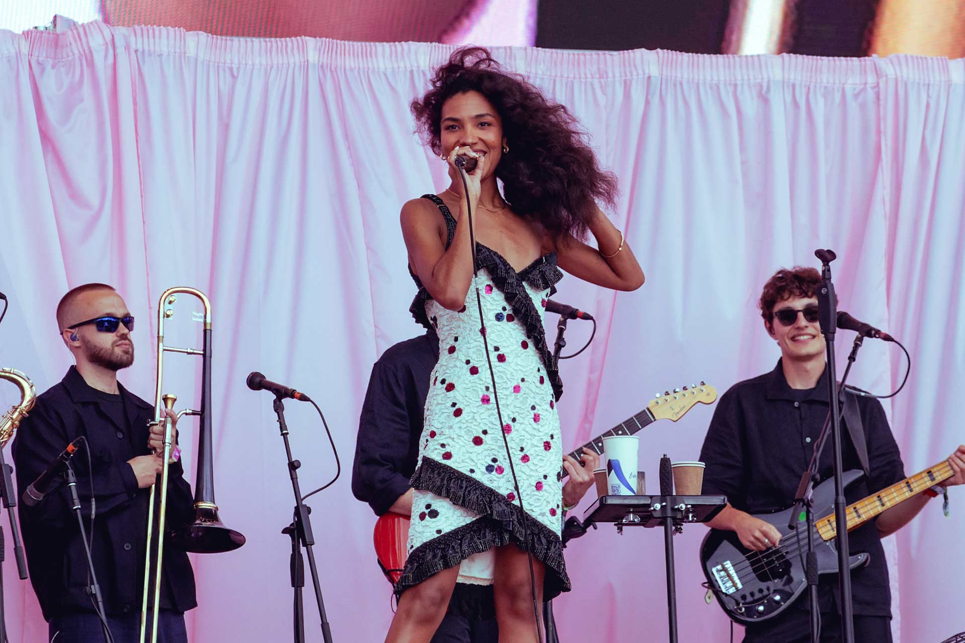 A woman on a stage in a white dress singing into a microphone.