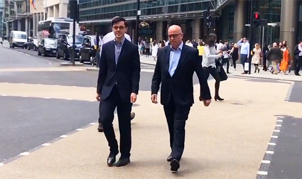 Two men walking across road in suits