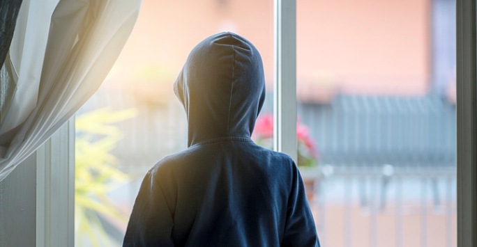 The back of a child in a hooded top, looking out of a window