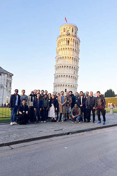A group of people posing for a picture in front of a leaning tower.