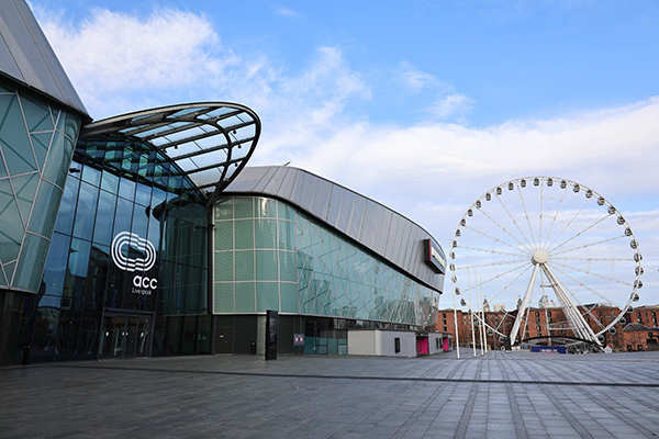 Image of a large building. A ferris wheel in the background.