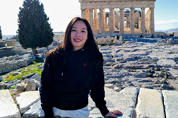 A person standing on a stone ledge in front of a building.