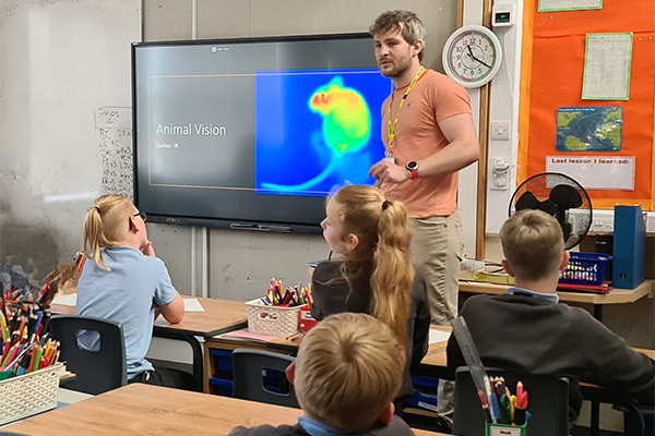 A student explaining something to school children.