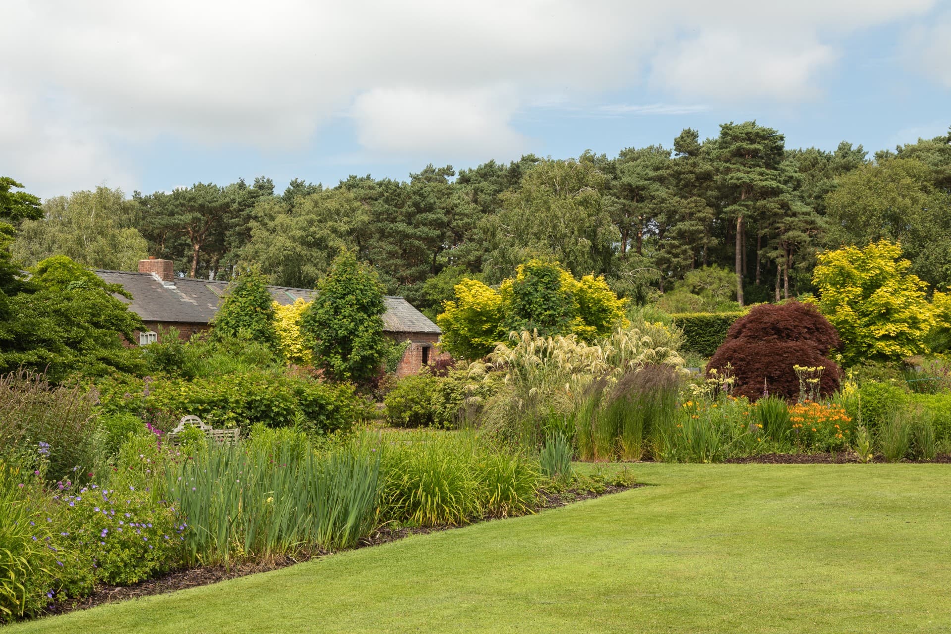 Ness Gardens potting sheds surrounded by green lawn and flower beds
