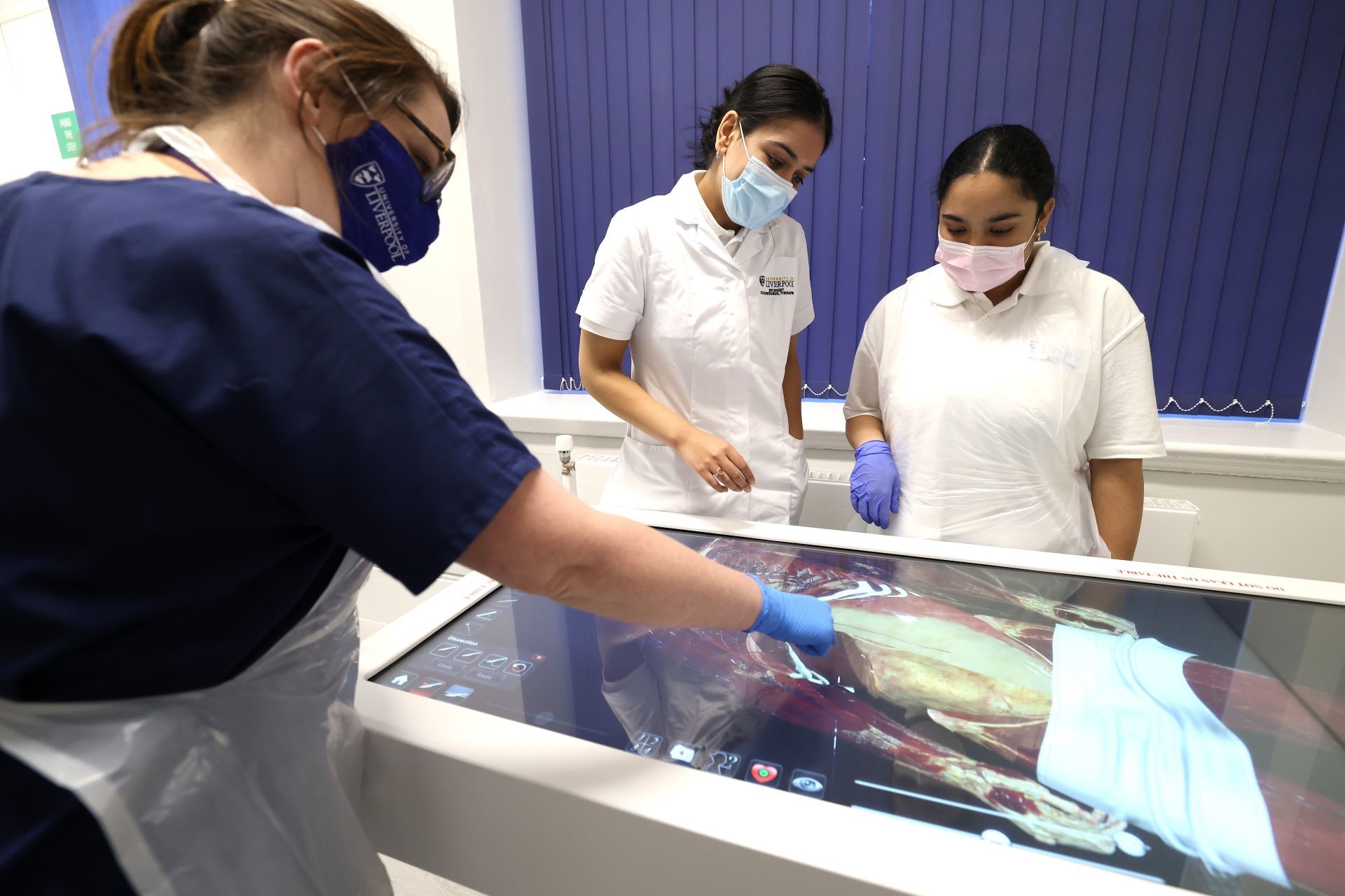 Three people stood around a piece of medical research equipment, carrying out work.