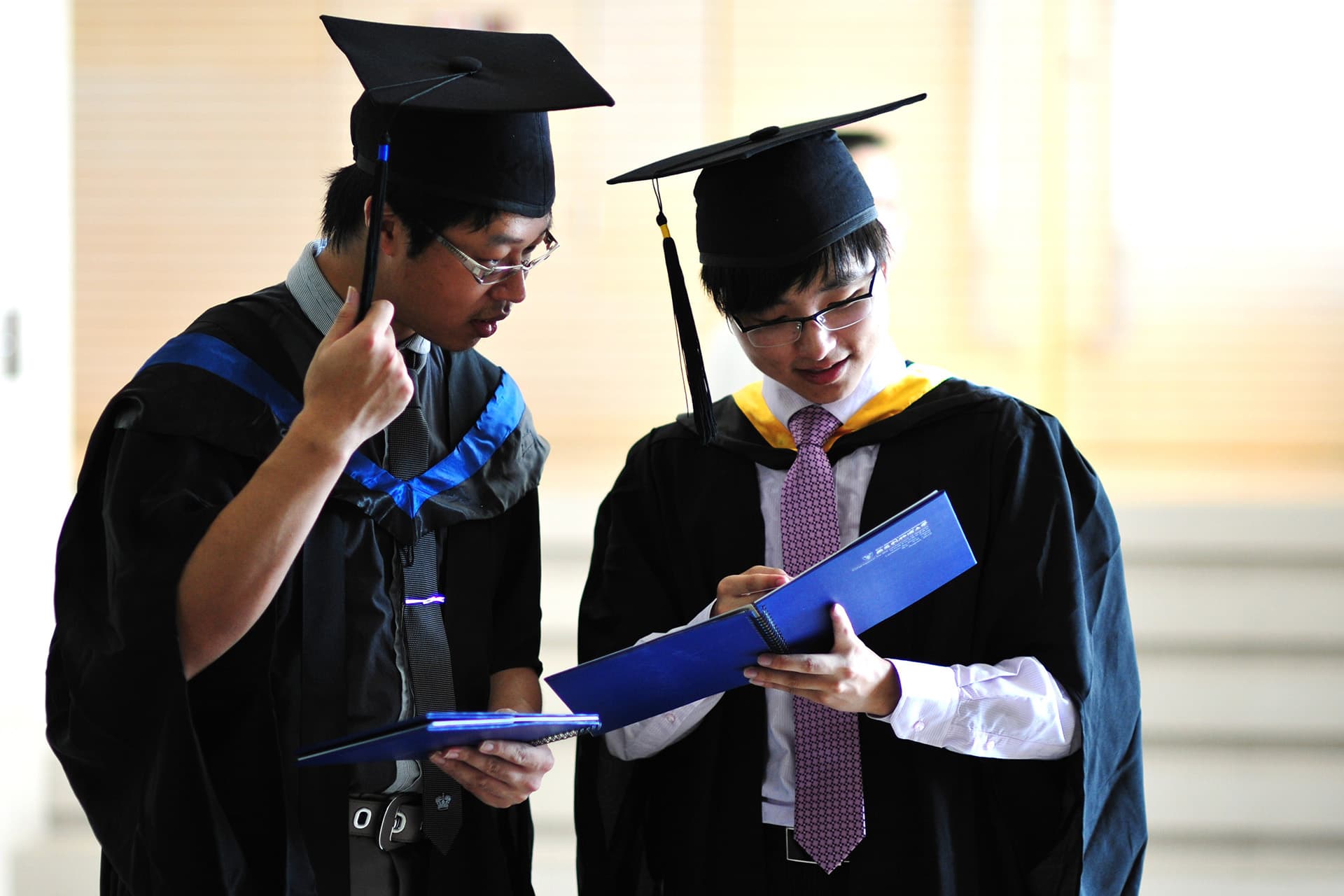 Two XJTLU students at graduation looking at the programme