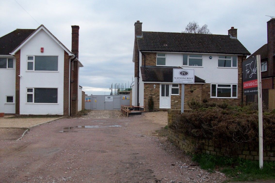A new house being built in a gap between and behind two existing houses
