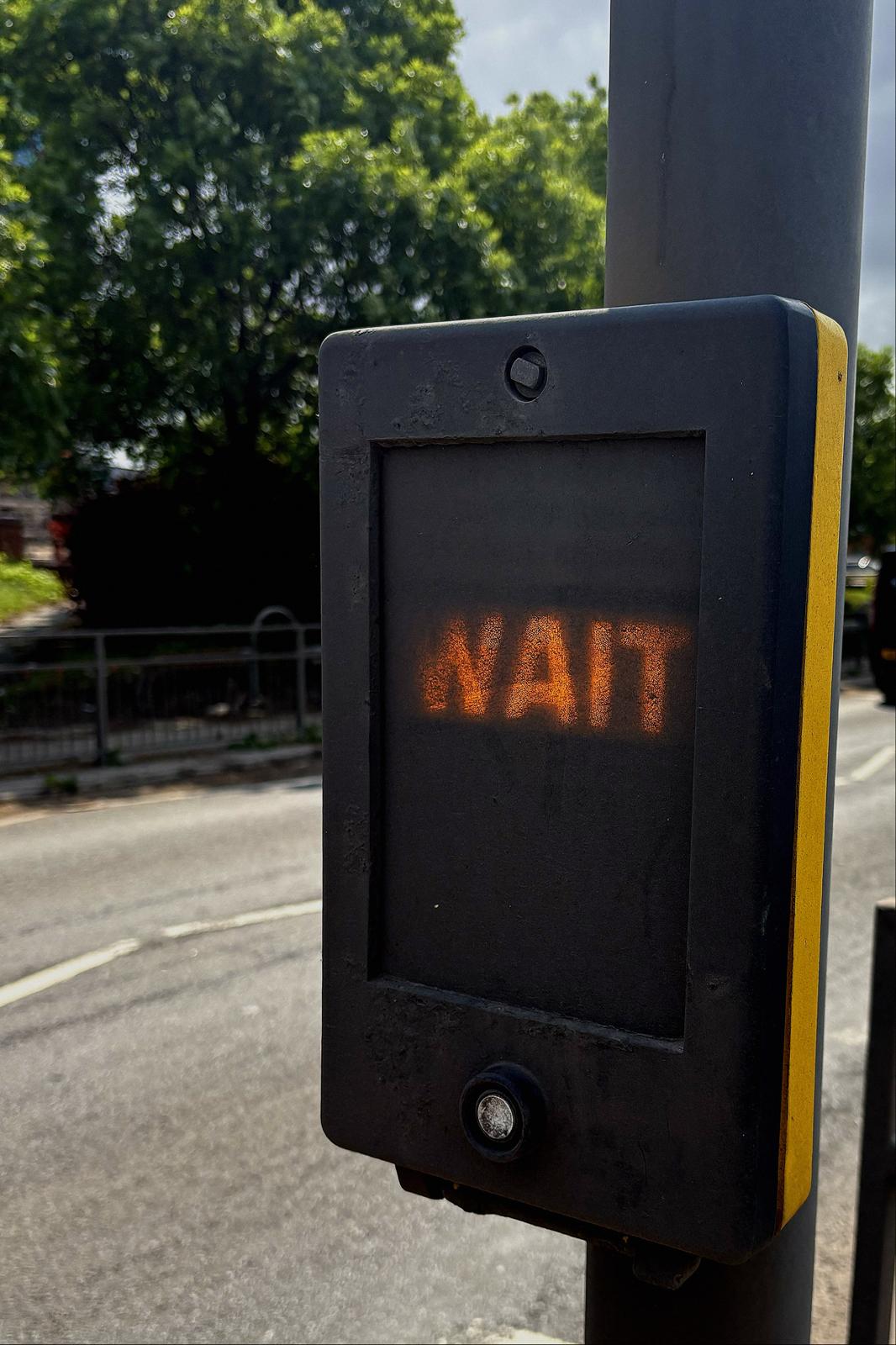 A pedestrian crossing in Bootle shows the word “WAIT” partially obscured by a layer of grey dust.
