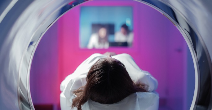 Person in an medical scanning machine with healthcare professionals in the distance
