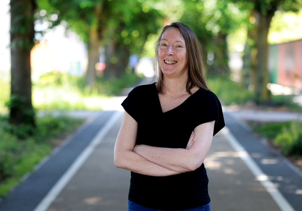 A person standing on a tree lined path