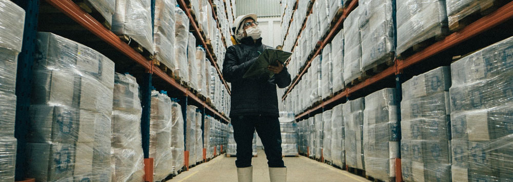 Person wearing a mask between warehouse shelves