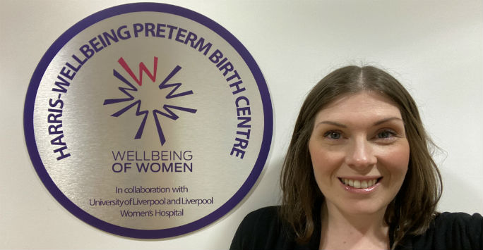 Researcher standing next to Harris Wellbeing Preterm Birth Centre plaque