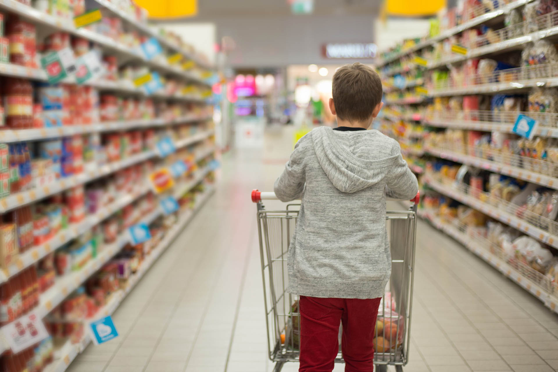 Boy in supermarket aisle with trolley