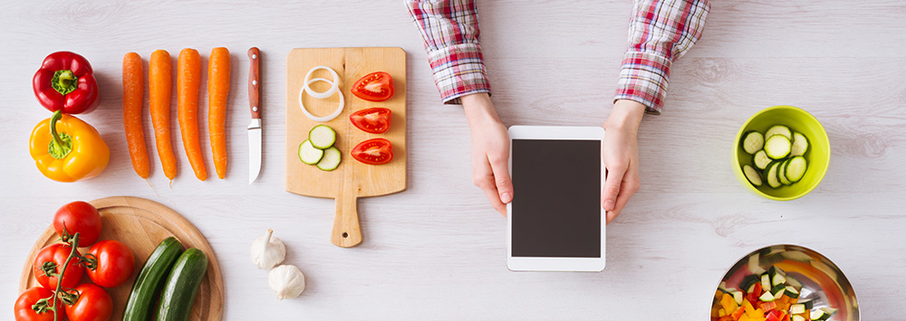 Recipes lined up on a table with someone holding and iPad