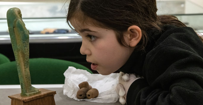 Young girl looking at Egyptian sculpture