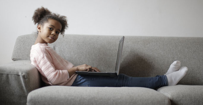 Young girl sitting on a couch with a laptop