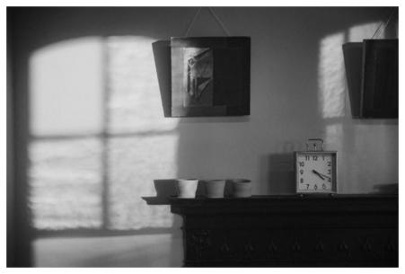 A black and white film still of a wall with light shining on it through a window