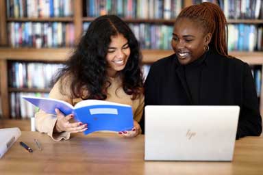 Two students sitting at a desk reading.