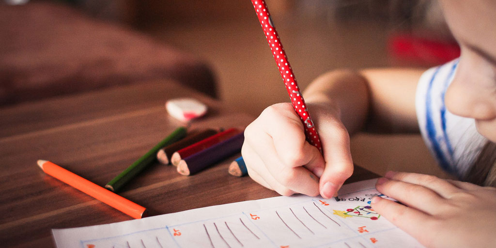 Child writing with crayons