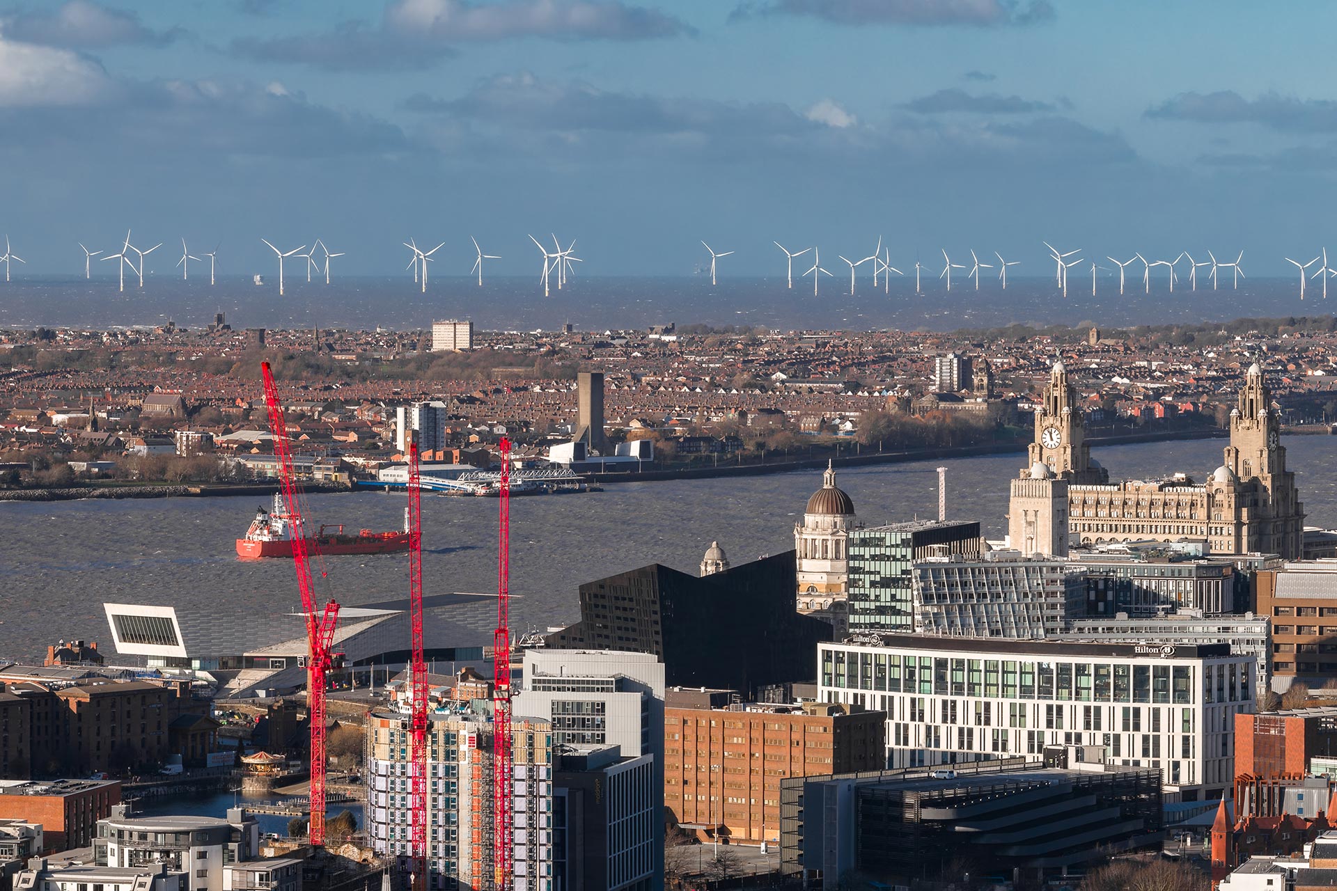 Photograph of Liverpool's skyline taken from the city, looking out across the River Mersey and over to Wirral, with wind turbines in the background