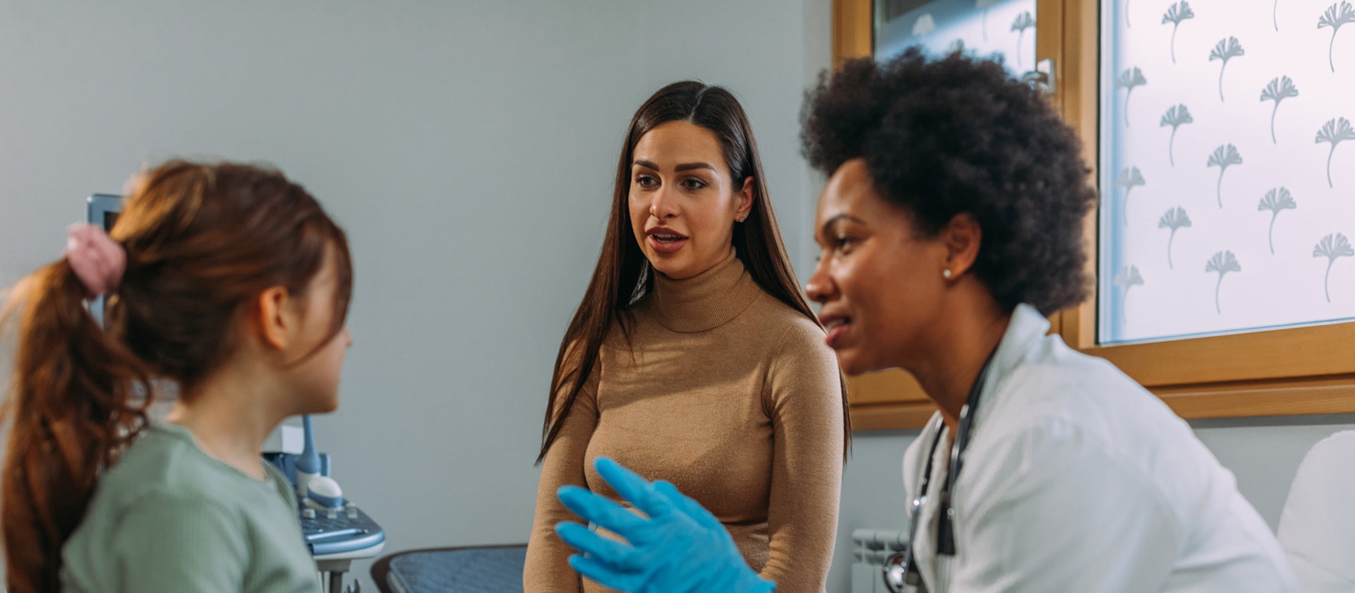 Female doctor talking to Mother and young girl in doctor's office