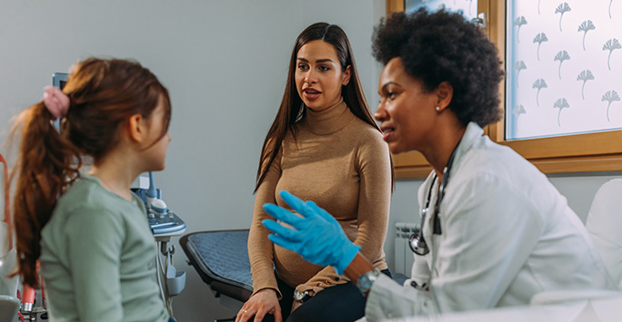 Female doctor talking to Mother and young girl in doctor's office