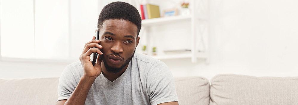 Young man on mobile phone sitting on couch