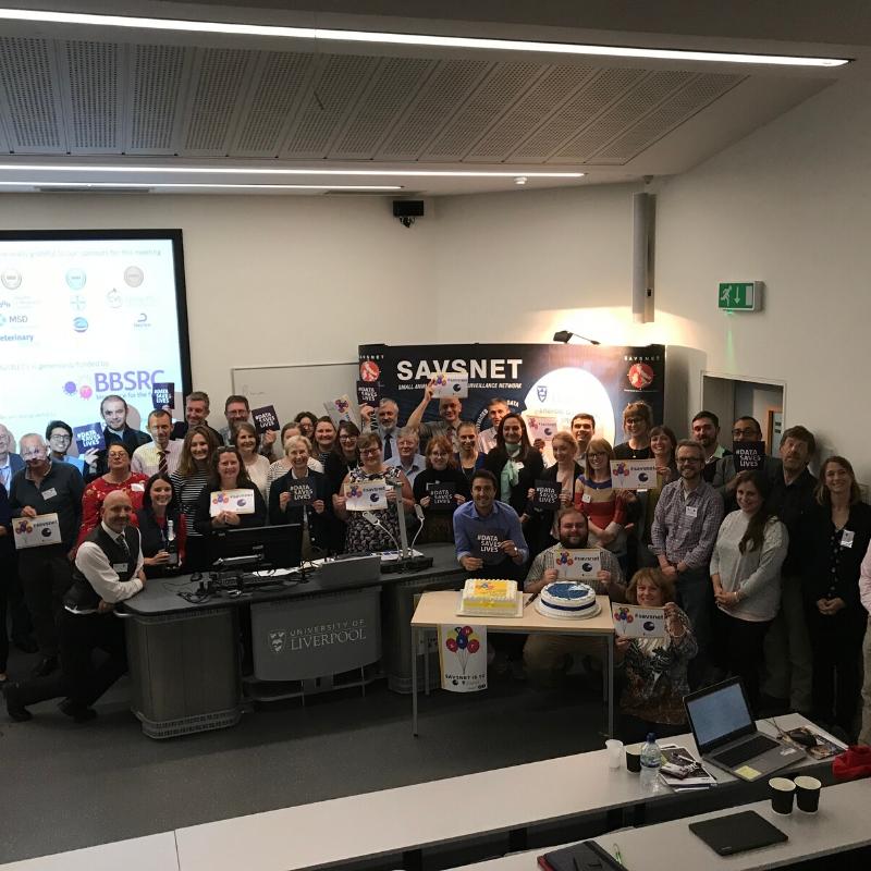 Large group of people standing together in lecture theatre