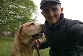 Male wearing a baseball cap pictured with yellow labrador