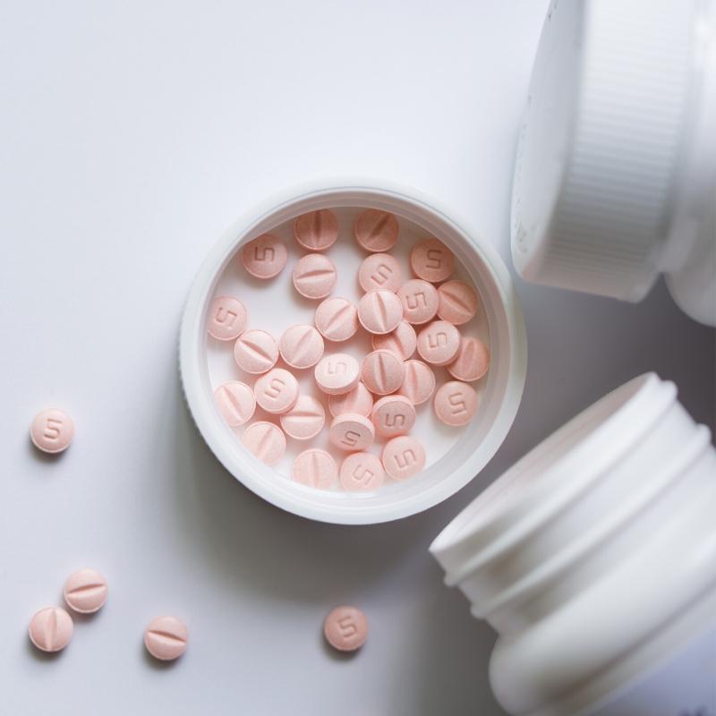 Pot of tablets with pink tablets poured in the lid