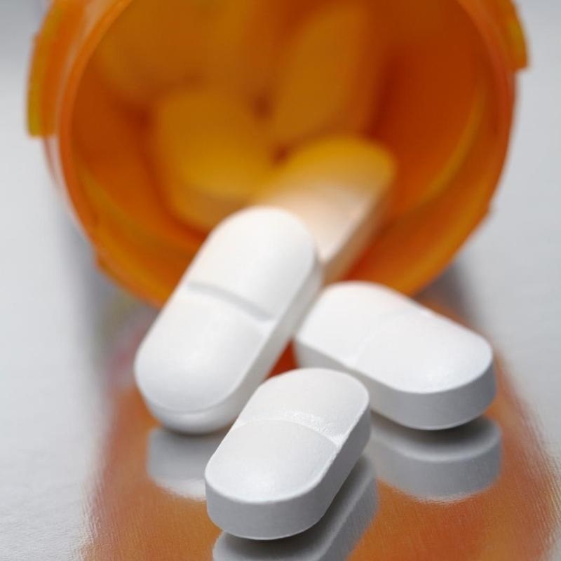 orange medication tub with white caplets scattered