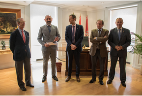 Five men in suits standing together and smiling in a grand room