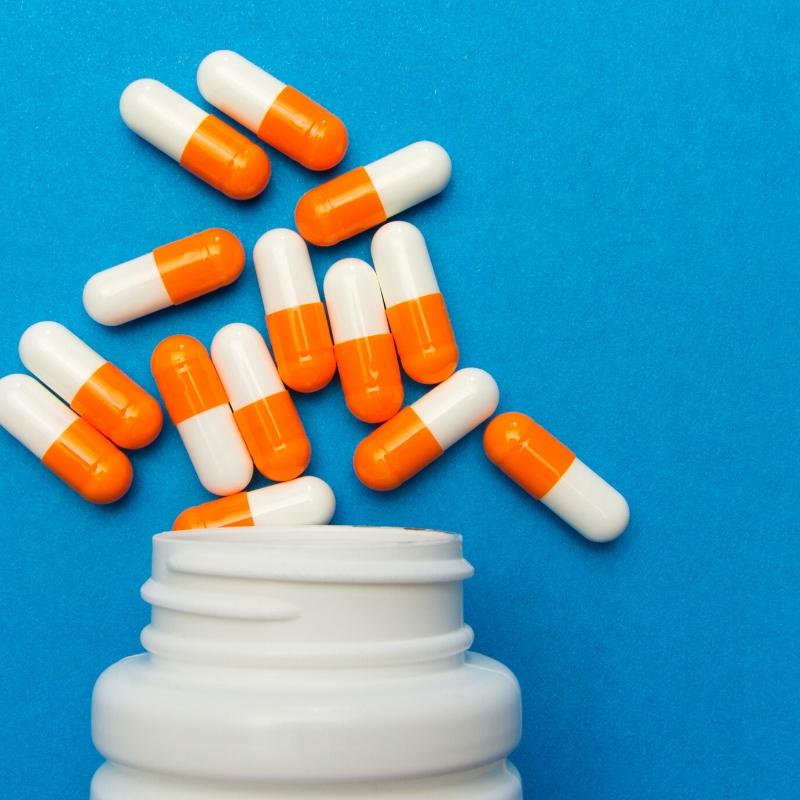 Capsules spilling out of a pot on a blue background