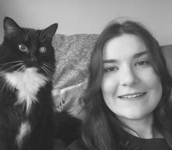 Female with long dark hair pictured with a black and white cat