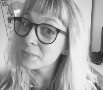 Greyscale image of white female with long blonde hair wearing glasses