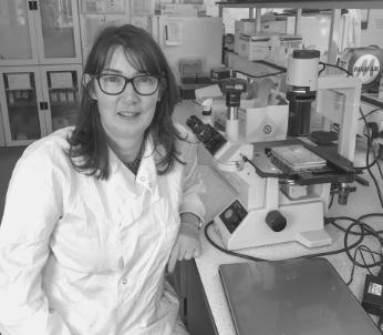 Greyscale image of white female with long dark hair in a laboratory setting