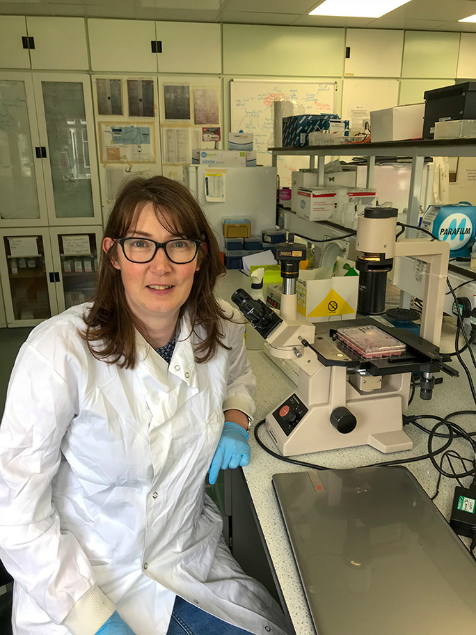 Female in white lab coat sitting in lab