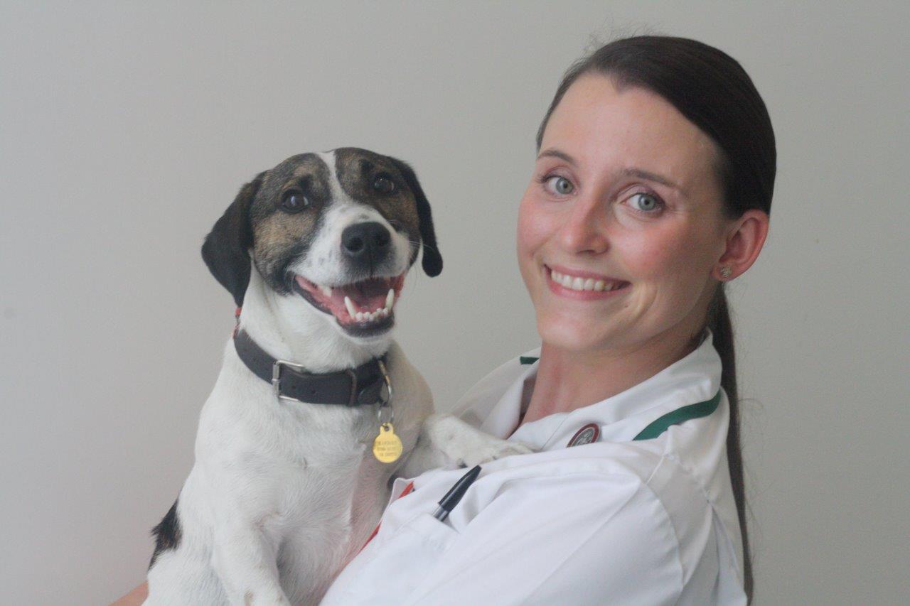 female with long dark hair holding a Jack Russell